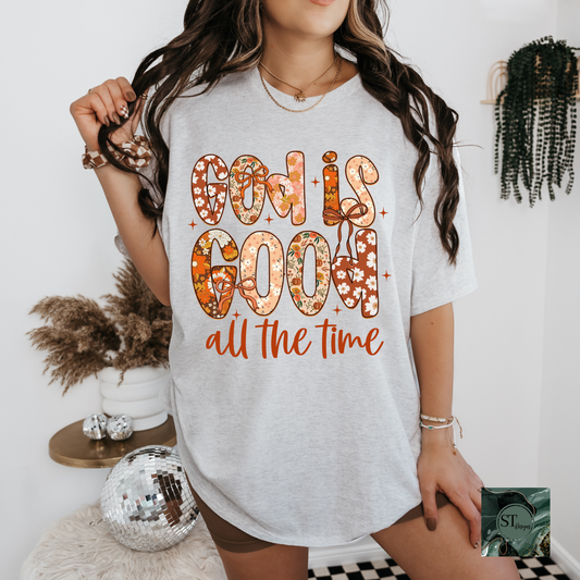Person wearing a white t-shirt with 'God is good all the time' text in an orange font.