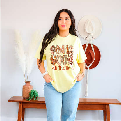 Woman wearing a yellow 'God is Good all the time' t-shirt in a home setting.